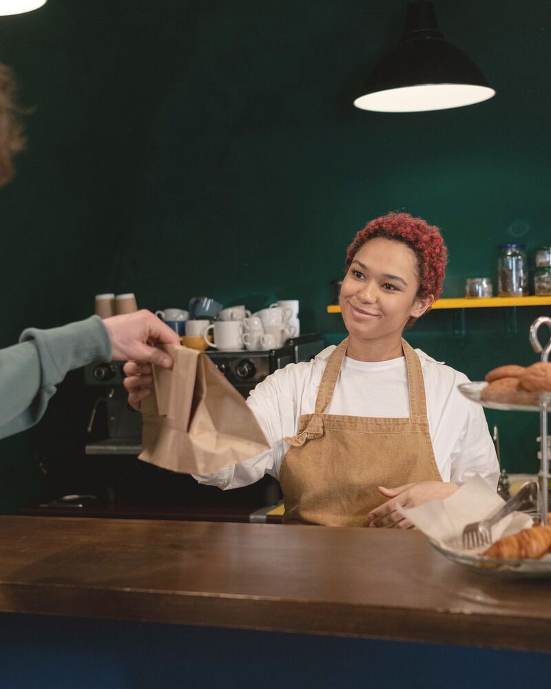 Encargada de una cafetería entrega un pedido a un cliente en el mostrador