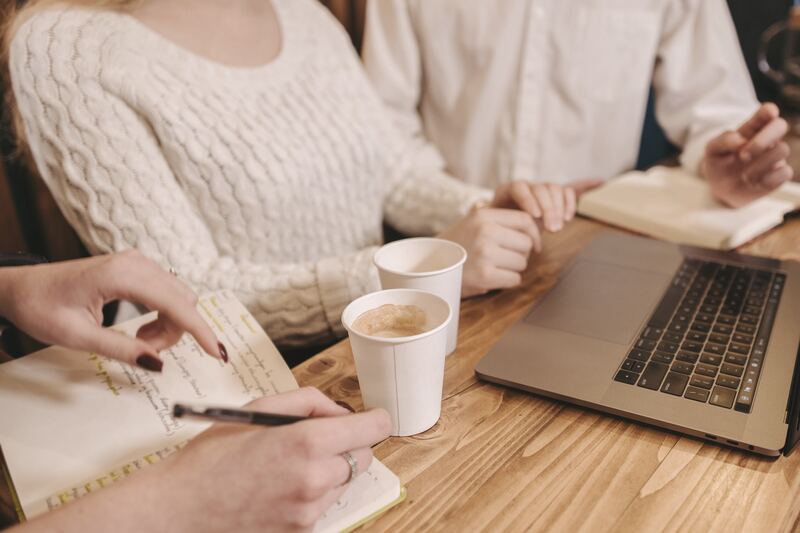 Sesión de trabajo en una mesa con cuaderno, café y portátil